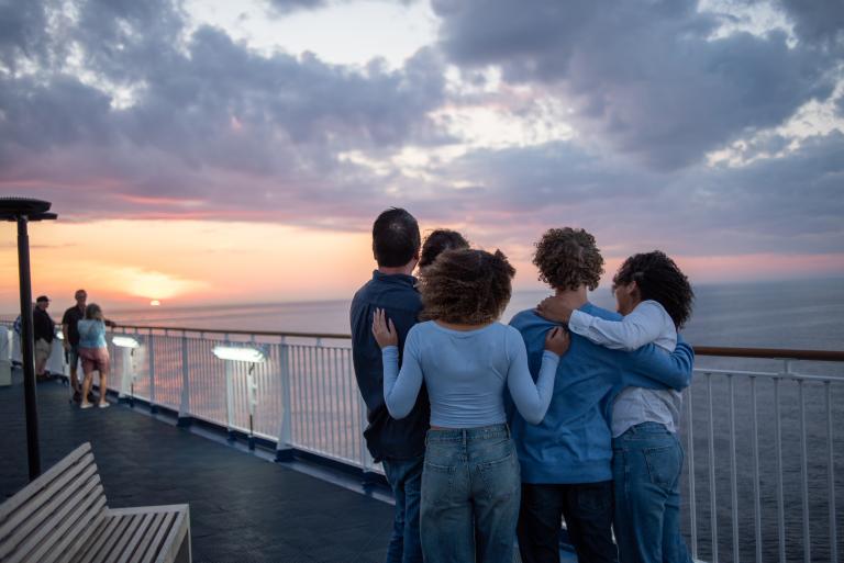A family embraces each other as they watch the distant sunset